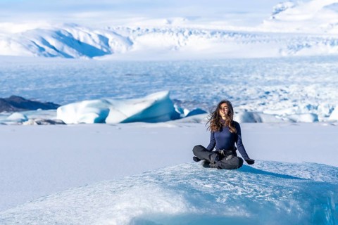 A woman is sitting on a block of ice in the snow. Concept of solitude and tranquility, as the woman