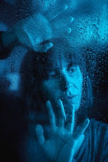 Sad look of a young caucasian woman looking at a rainy night in the covid19 quarantine with her