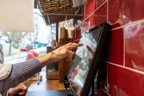 Staff member using a modern point of sale - pos - system with a touchscreen display, processing