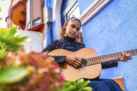Low angle view photo of a beauty young african american woman playing the guitar next to colorful