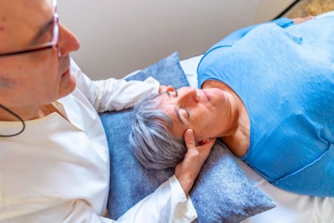 Qi gong masseur doing a massage to the head of a mature woman