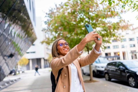 Latin woman in casual business clothes visiting a city taking photos from street views