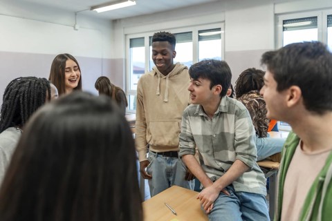 Multi ethnic group of high school students enjoying teamwork while collaborating on a school