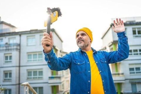 Low angle view portrait of a mature male vlogger waving at audience streaming in the city using