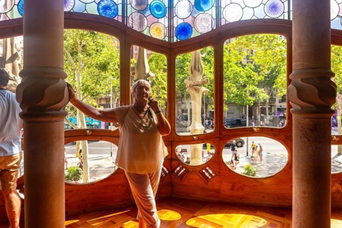 Senior woman looking through colorful stained glass windows and bone like columns in casa batllo, a