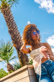 Vertical low angle view photo of a sensual latin woman with curly hair drinking milkshake standing
