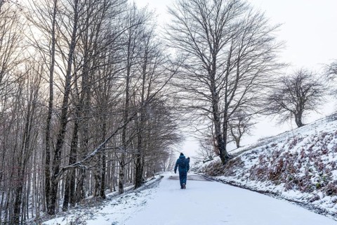 A young man walking on the path to climb Mount Aizkorri in Gipuzkoa. Snowy landscape by winter