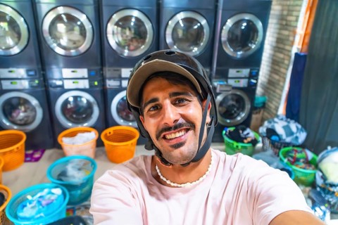 Young male tourist wearing helmet taking a selfie in a laundromat while traveling in cebu,