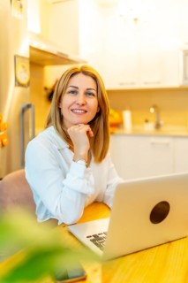 Vertical portrait of an elegant blonde woman working from home using laptop
