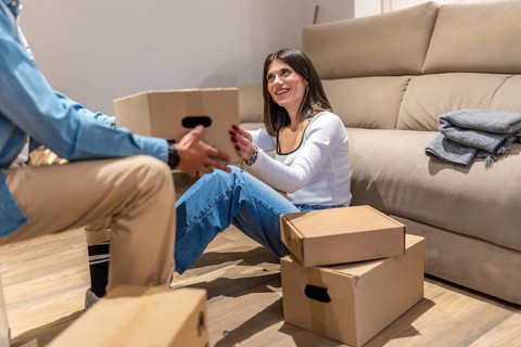 Happy couple unpacking cardboard boxes in new home living room, starting new life chapter together