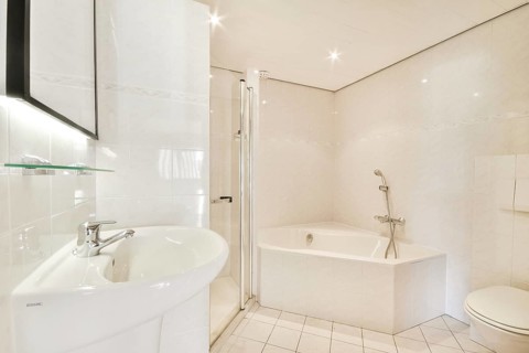 A contemporary bathroom featuring a sleek shower stall, elegant bathtub, and stylish fixtures. The