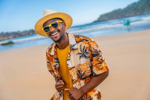African american man in summer clothes dancing happily on the beach
