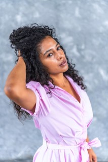 Vertical close-up portrait of a sensual latin woman with elegant pink clothes posing looking at