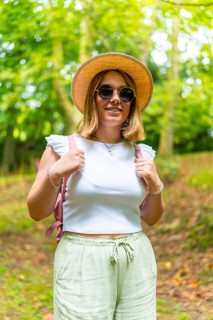 Vertical portrait of a caucasian young adult woman in summer clothes and sunglasses smiling while