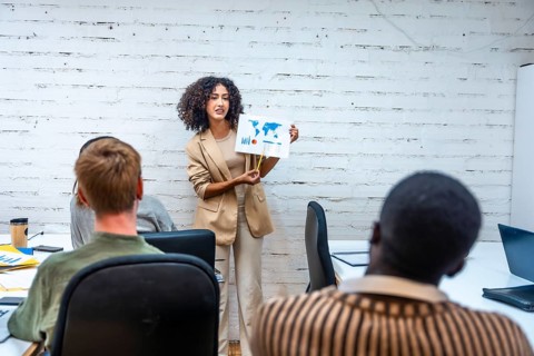 Caucasian young woman showing an infographic during a coworking meeting with diverse people