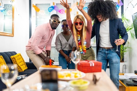 Multi-ethnic friends joking playfully having fun in a home birthday party