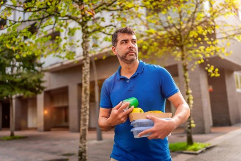A man delivering takeaway food and beverages walking along the city