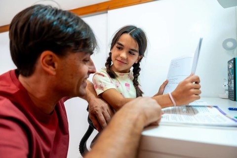 Father and daughter at a desk during a daily study session, working through homework in a cozy home