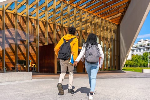 Rear view full length photo of an african young couple walking to university holding hands