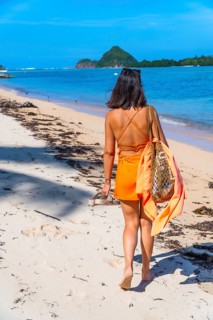 Young woman walking barefoot on white sand at lakdayan beach, coron island, enjoying summer