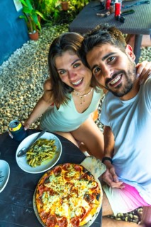 Tourists taking a selfie while having lunch with pizza and pasta in a restaurant in siargao island,