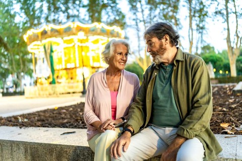 Senior couple sitting and chatting in the city next to night fair