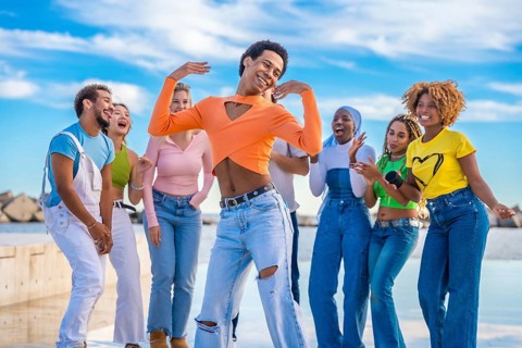 Transgender person dancing happily with multi-ethnic friends outdoors