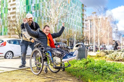 Caregiver pushing a joyful disabled man in a wheelchair, soaking up the sunshine while enjoying a
