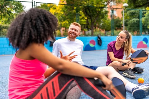 Latin woman talking with friends after playing pickelball in an outdoor court