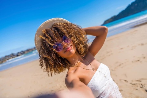 Personal perspective of a beauty brunette woman with curly hair and summer clothes taking selfie at