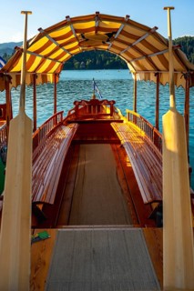 Wooden pletna boat with striped canopy and oars awaits tourists on scenic lake bled in the julian