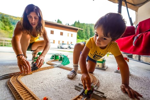 Mother and son enjoying quality time together, playing with a toy train set on a patio during their