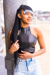 Black ethnic girl with braids with leather top and cowboy pants. Enjoying the summer holidays next