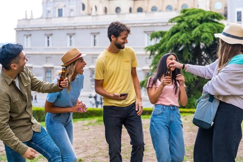 Multi-ethnic group of friends partying in a city park with beers. summer fun, greetings to the new