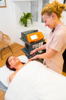 Vertical photo of a friendly female physiotherapist treating pain of a patient using Indiba
