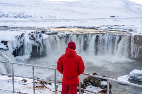 A man with his back turned at the beautiful Godafoss waterfall in winter in Iceland. winter tourism