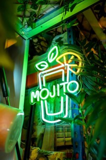 Vertical photo of a mojito cocktail glass in a neon light panel in a bar
