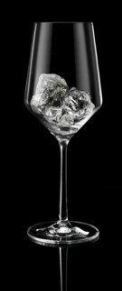 Wine glass filled with ice cube cubes in front of a black background, studio shot