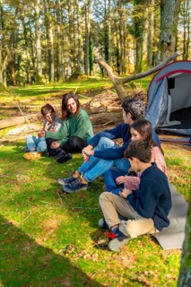 Vertical full length photo of a caucasian family sunbathing enjoying nature during camping weekend