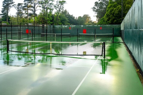 Multiple outdoor pickleball courts creating reflections from the wet surface after a rain,