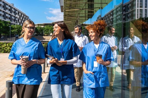 Healthcare team including diverse doctors and nurses walking and talking outside a modern clinic,