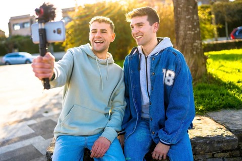 Two young content creators filming a vlog in a park, enjoying the sunny weather and sharing their
