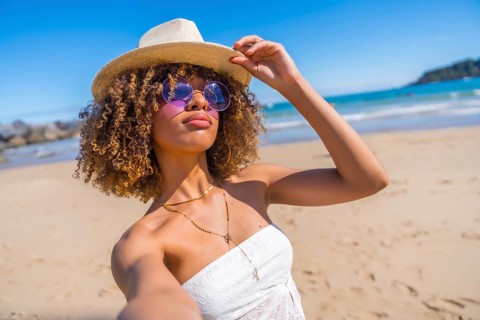 Personal perspective of a beauty latin young woman wearing sunglasses and sun hat taking a selfie