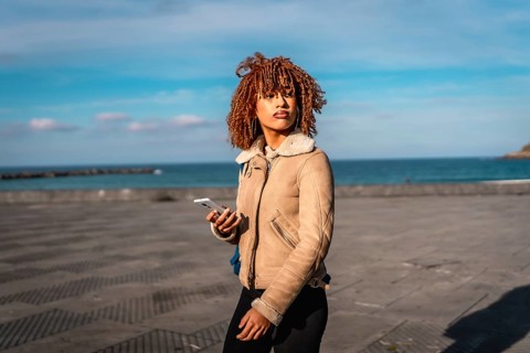 Beauty latin young woman enjoying walk in the promenade using mobile phone
