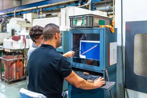 Rear view of a female manager and engineer using computer in a cnc metallurgic factory