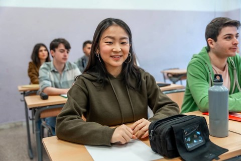 Young asian student smiling while engaging in a lesson with classmates in a vibrant university