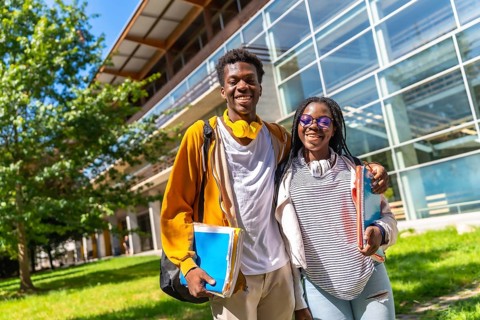 Portrait of two proud and happy african university colleagues standing outdoors in the campus
