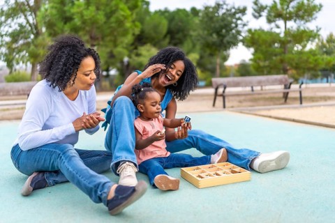 Multi-generational female african woman sitting on the park with toys for the baby