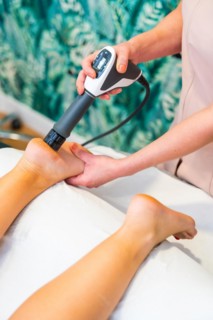 Vertical close-up of a physiotherapist using innovative treatment with shock waves in a patient in