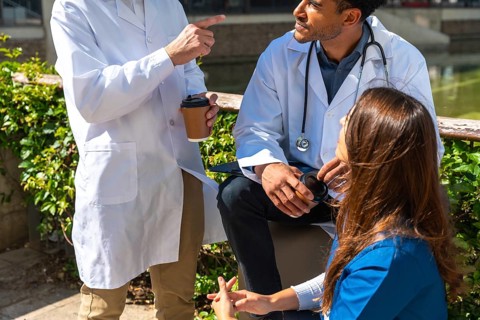 Diverse medical professionals wearing lab coats and scrubs engaging in thoughtful discussion and
